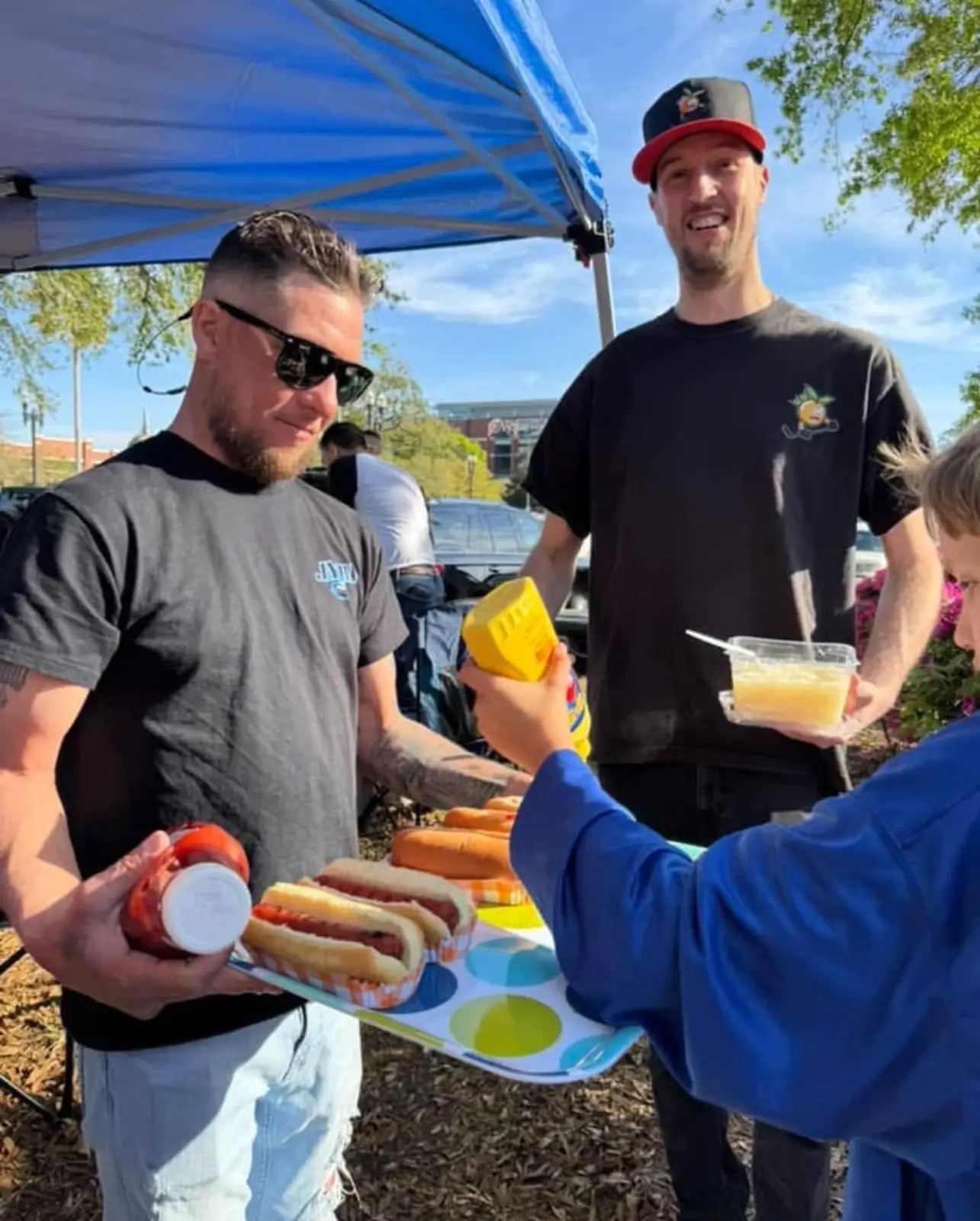 Matt and Mike serving hot dogs at the tailgate